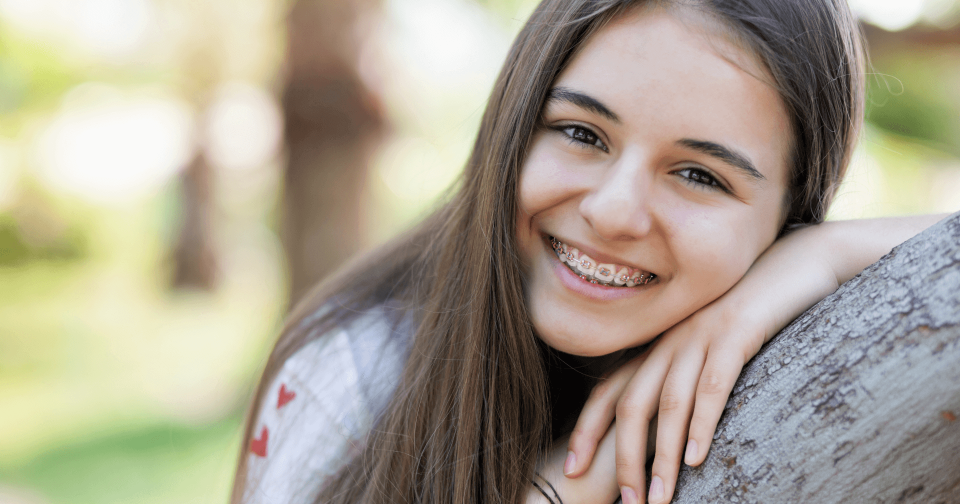 Photo of a young girl with braces sitting in the outdoors.